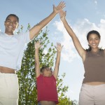 Portrait of a young couple and a child with their arms outstretched --- Image by © Royalty-Free/Corbis