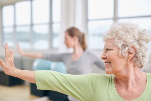 Close-up shot of elderly woman doing stretching workout at yoga class. Women practicing yoga at health club. ** Note: Shallow depth of field